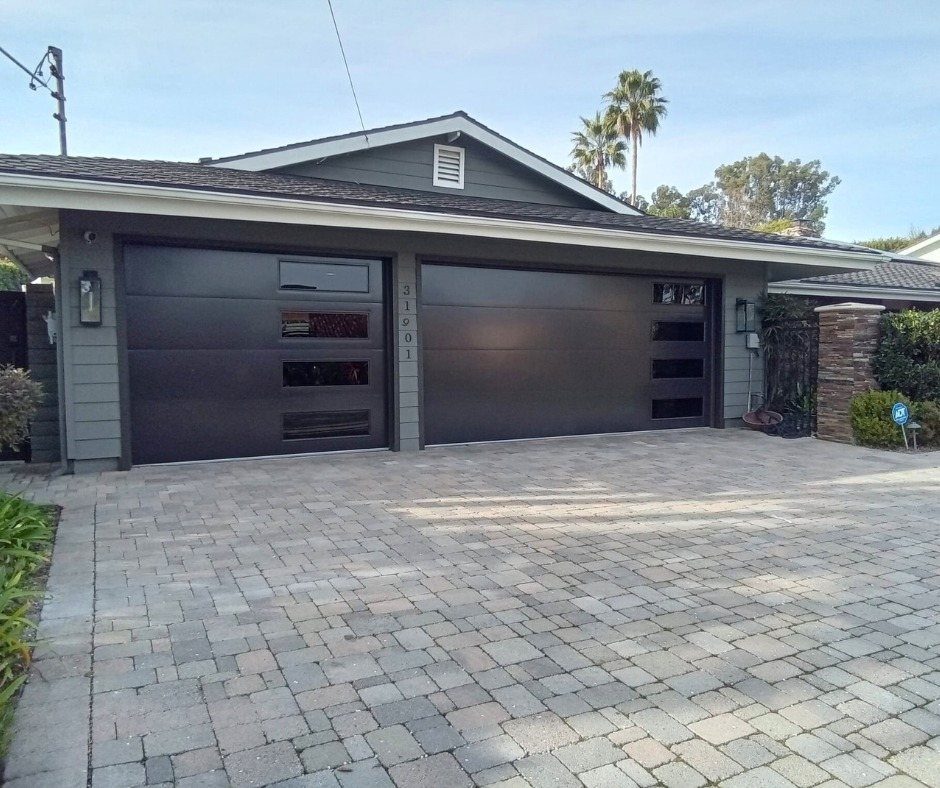 Two dark brown modern garage doors with horizontal glass windows on a grey house.