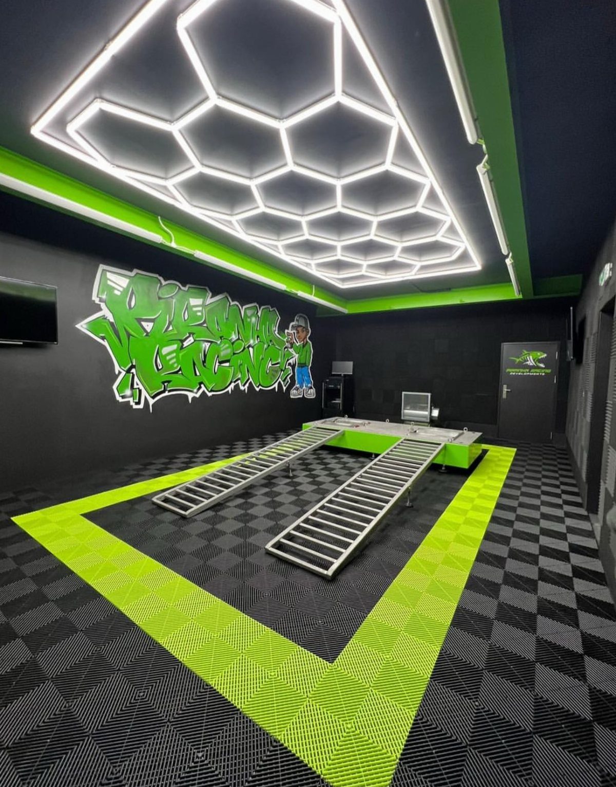 Hexagonal LED light fixture illuminating a modern black and green themed garage interior.