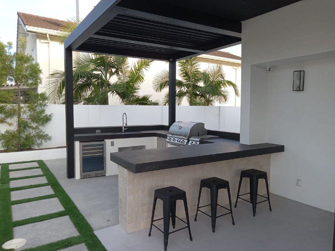 Backyard Barbeque Design: 12 BBQ Island Ideas for Outdoor Cooking 6 Modern outdoor kitchen island with black countertops, built-in grill, and three black bar stools.