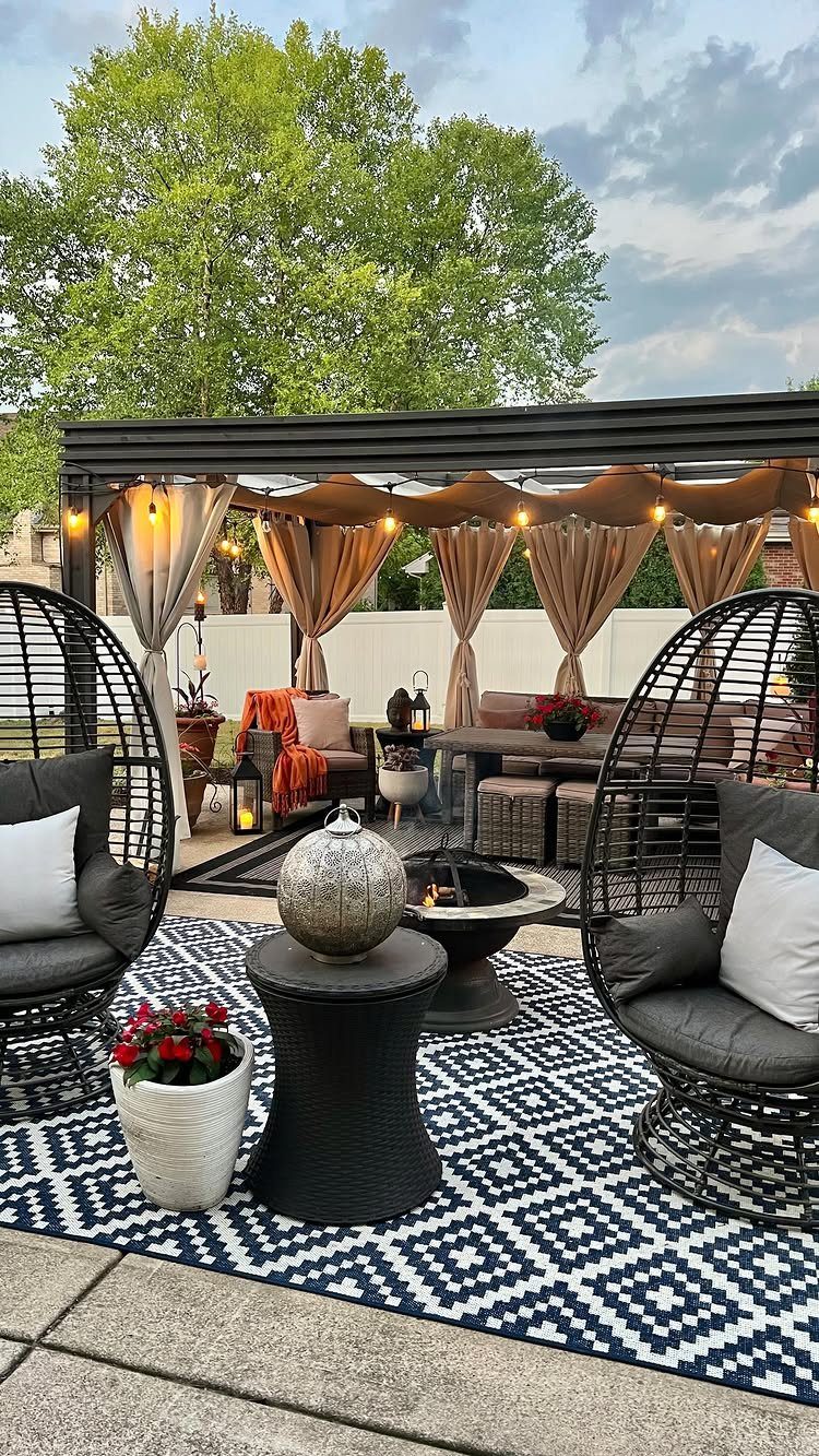 13 Backyard Entertaining Area Ideas for Every Season 9 Blue and white patterned outdoor rug under black wicker egg chairs and a fire pit.