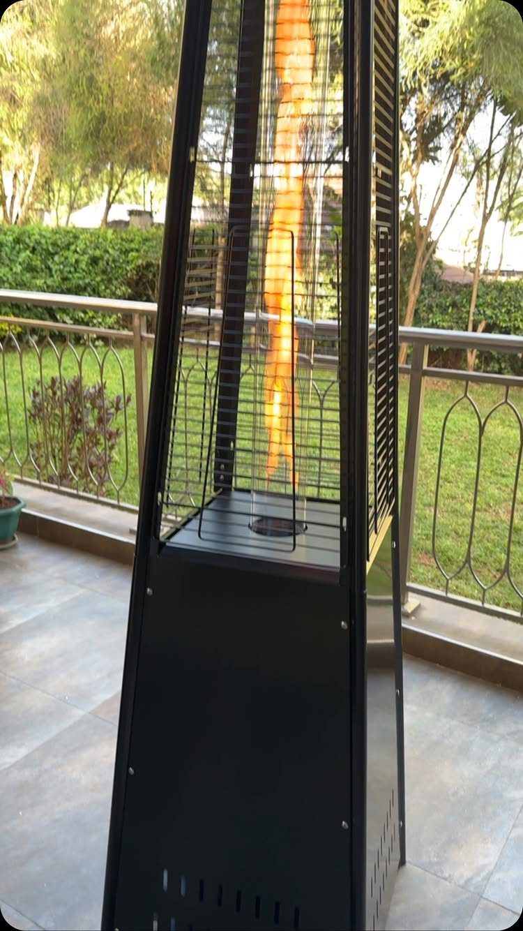 13 Backyard Entertaining Area Ideas for Every Season 13 Black pyramid gas patio heater with a bright orange flame on a tiled balcony.