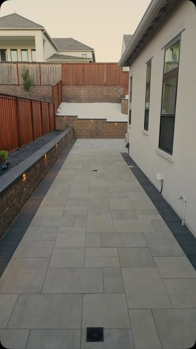 Paved stone patio with a low stone wall featuring small integrated outdoor lights.