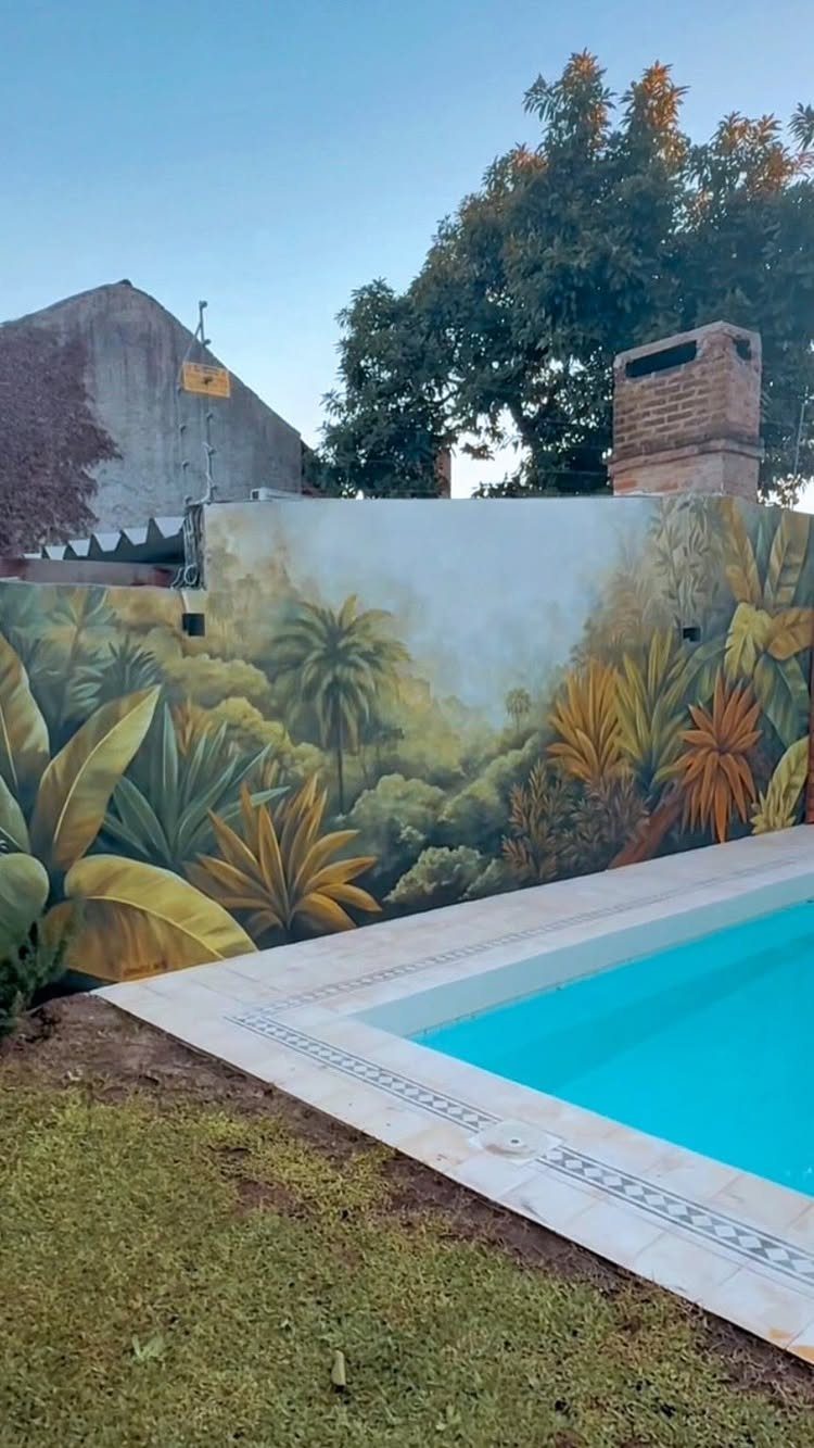 Tropical jungle mural painted on a wall next to a bright blue swimming pool.