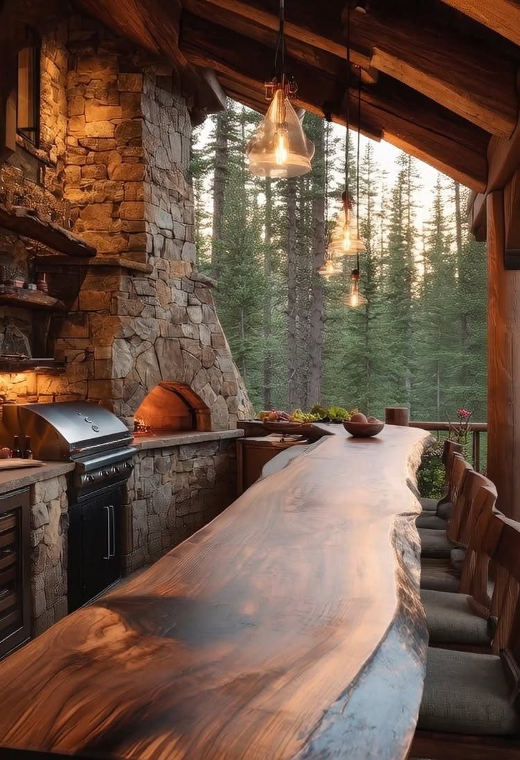 A rustic outdoor kitchen with a live-edge wooden bar and stone grill under a wooden roof.
