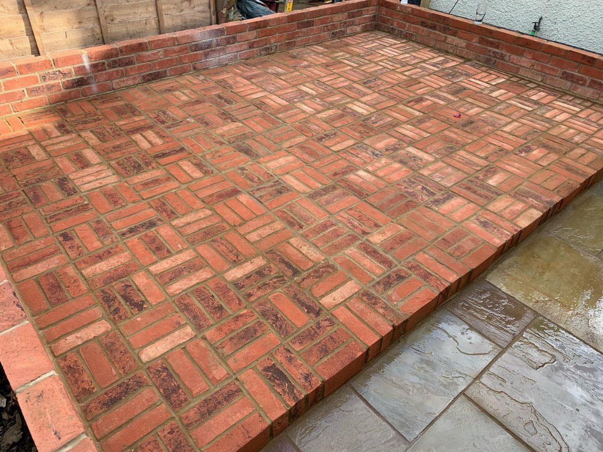 Red brick patio featuring a basket weave pattern enclosed by low brick walls.