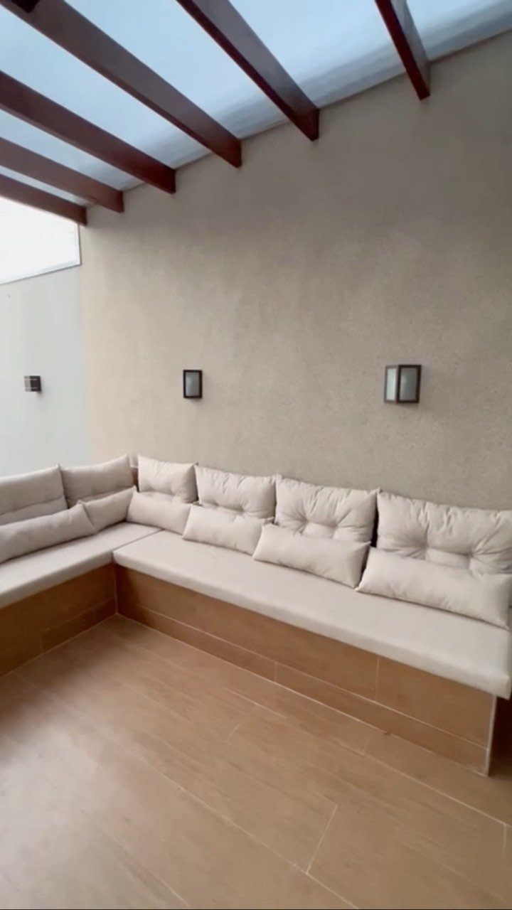 20 Covered Patio Ideas for Shade, Style and Year-Round Use 14 Built-in wooden corner bench with beige cushions under a translucent roof pergola.