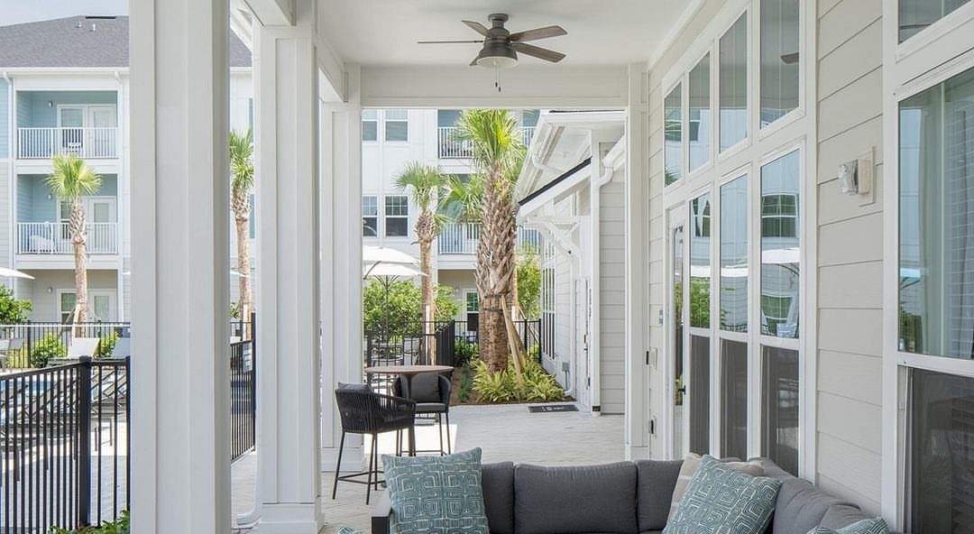 20 Covered Patio Ideas for Shade, Style and Year-Round Use 6 A dark ceiling fan mounted on a white covered patio ceiling overlooking palm trees.