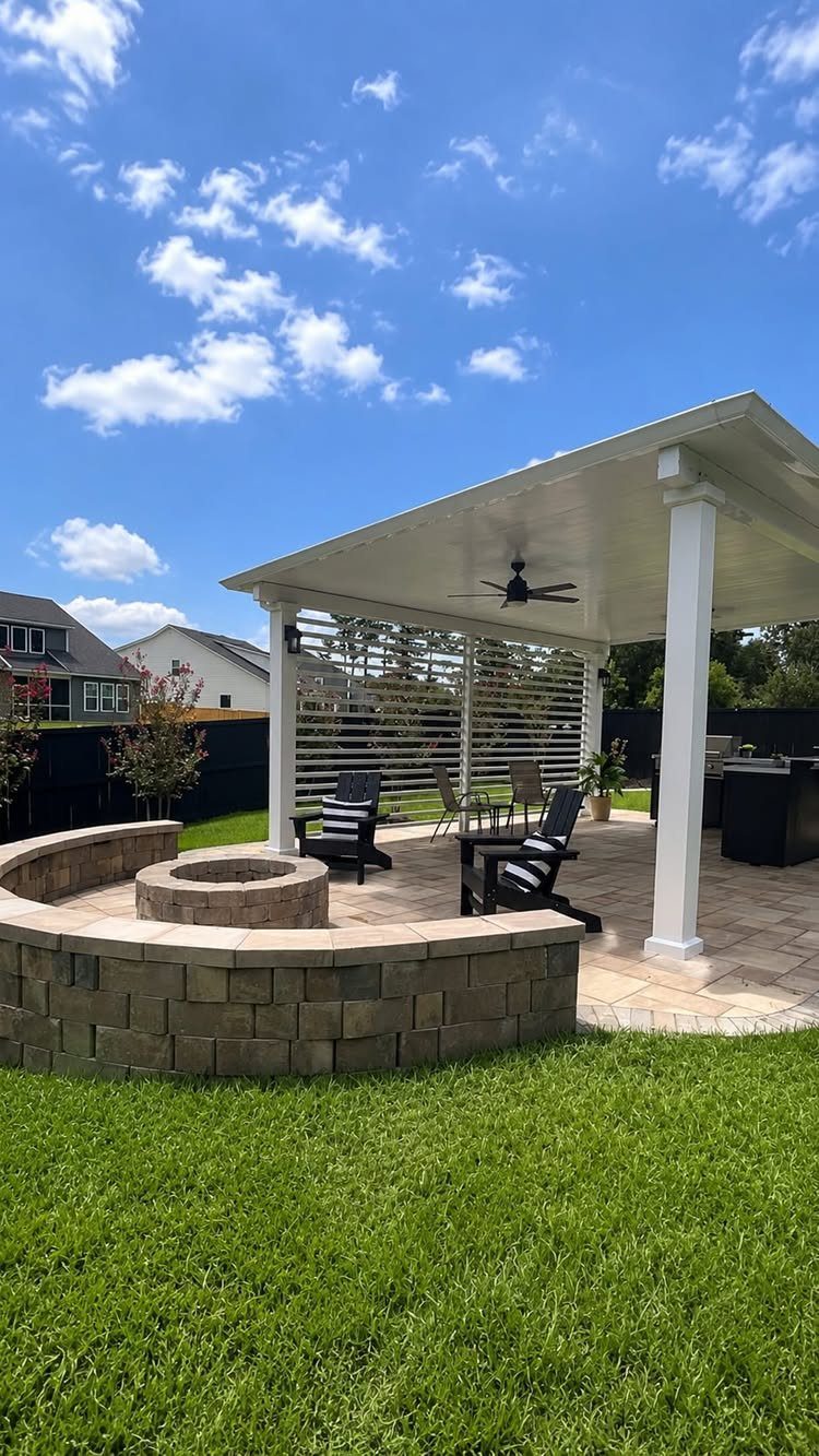 20 Covered Patio Ideas for Shade, Style and Year-Round Use 9 Stone fire pit in a green lawn positioned in front of a white covered patio.