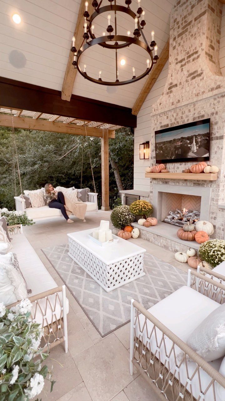 20 Covered Patio Ideas for Shade, Style and Year-Round Use 18 White wicker lounge furniture arranged around a coffee table and stone fireplace on a covered patio.