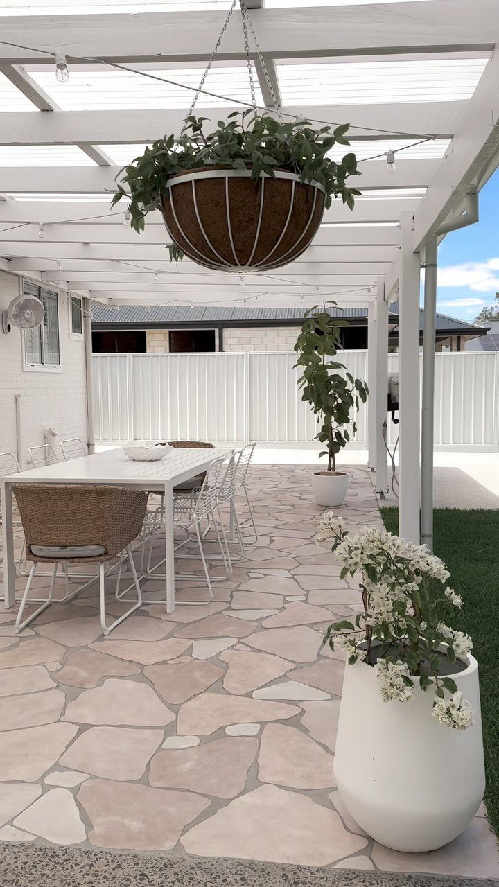 20 Covered Patio Ideas for Shade, Style and Year-Round Use 10 White patio structure with translucent roofing panels overlooking a dining area with potted plants.