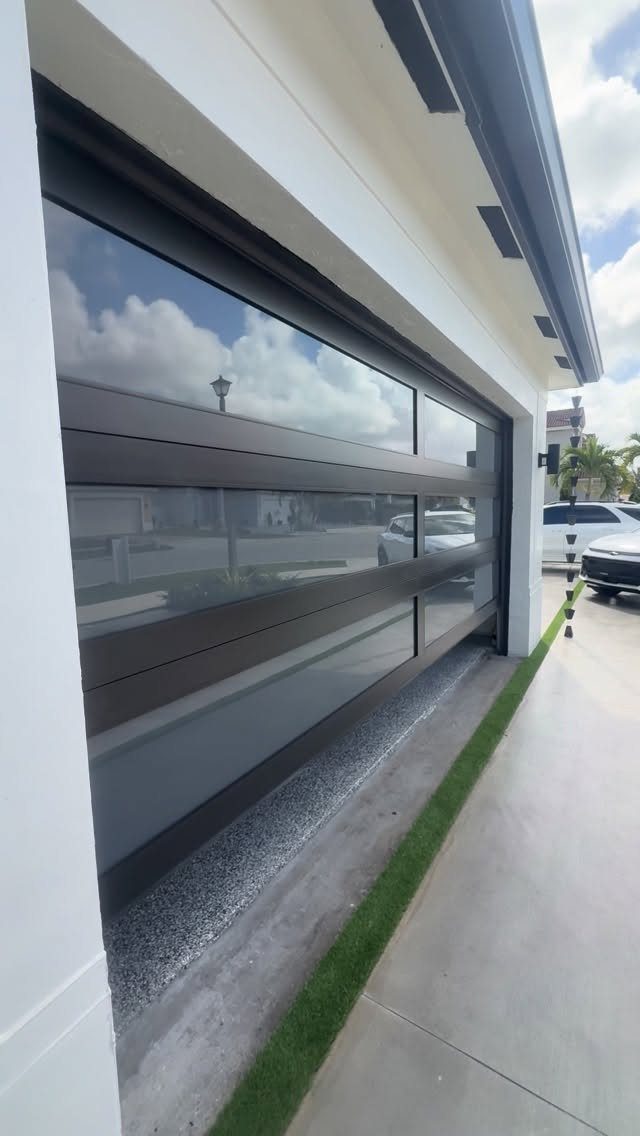 10 Curb Appeal Ideas for a Sharper Front Facade in 2026 9 Modern glass garage door with dark frames installed on a white exterior house wall.