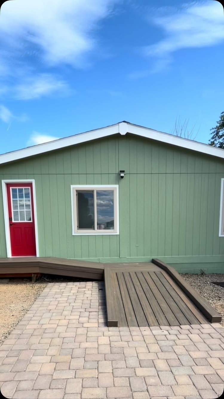 4 Deck Ramp Ideas for Every Yard and Budget 2 A dark brown wooden deck ramp connecting a green building to a brick patio.