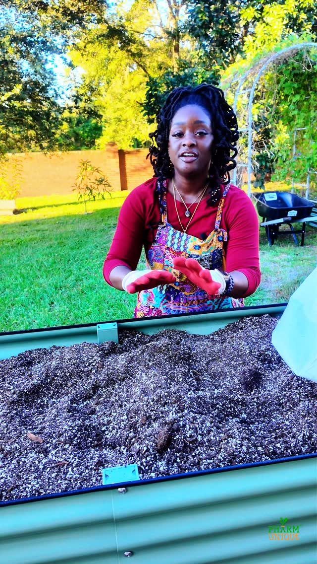 Easy Raised Garden: 9 Ideas for Any Budget and Skill Level 6 A woman stands behind a green metal raised garden bed filled with dark soil mixture.