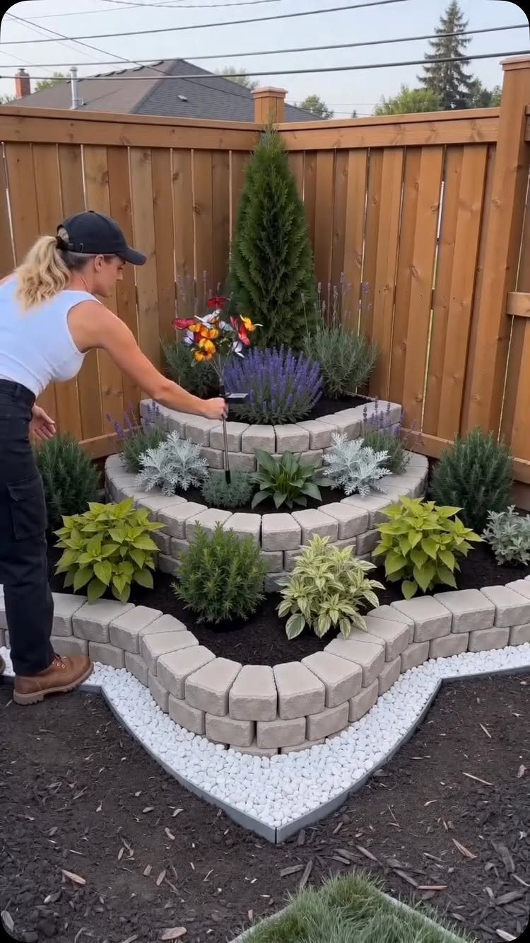 Easy Raised Garden: 9 Ideas for Any Budget and Skill Level 5 A woman gardening in a multi-level stone tiered planter bed filled with various green and purple plants.