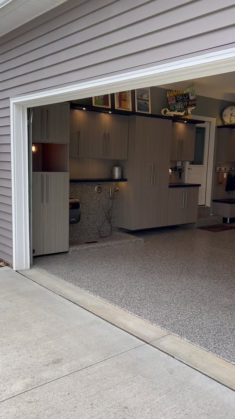 9 Garage Design Interior Ideas for Workspace, Storage and Style 6 Grey storage cabinets and black countertops installed inside a modern garage with epoxy flooring.