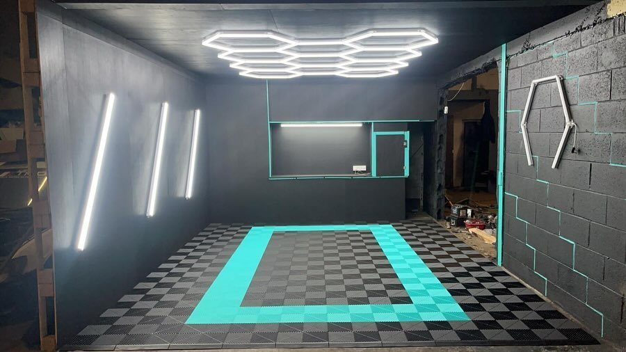 9 Garage Design Interior Ideas for Workspace, Storage and Style 5 Modern garage interior with hexagonal LED ceiling lights and vertical light bars on dark walls.