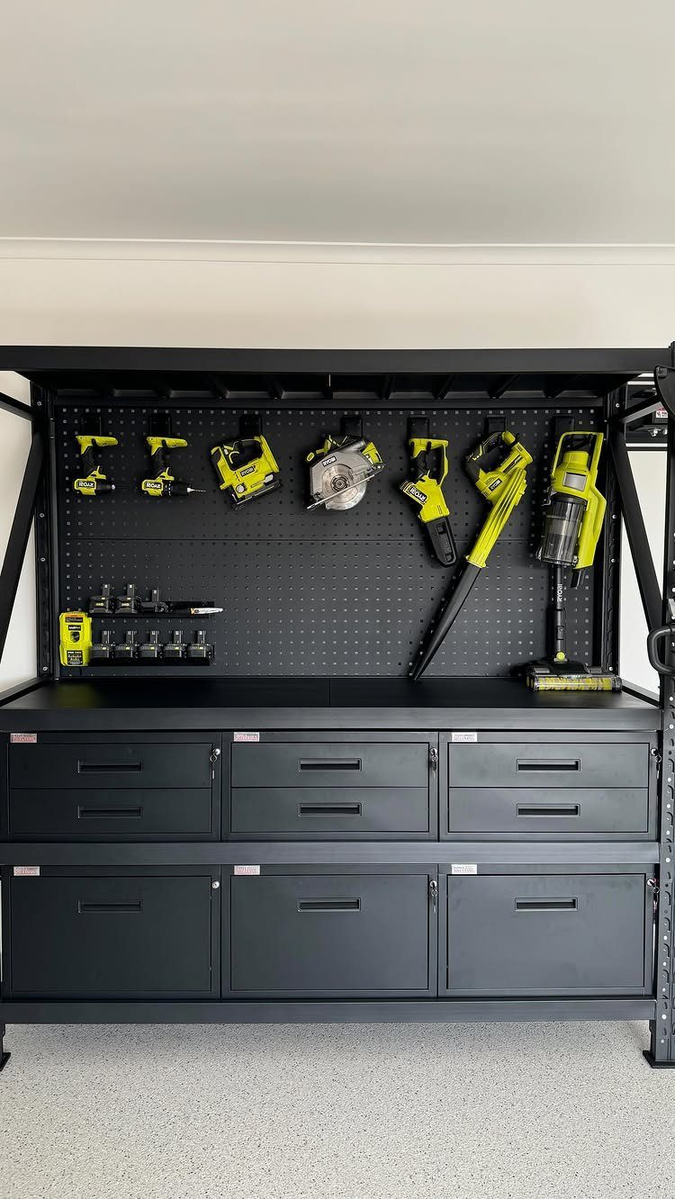 9 Garage Design Interior Ideas for Workspace, Storage and Style 4 Yellow power tools hanging from hooks on a black pegboard above a black workbench.
