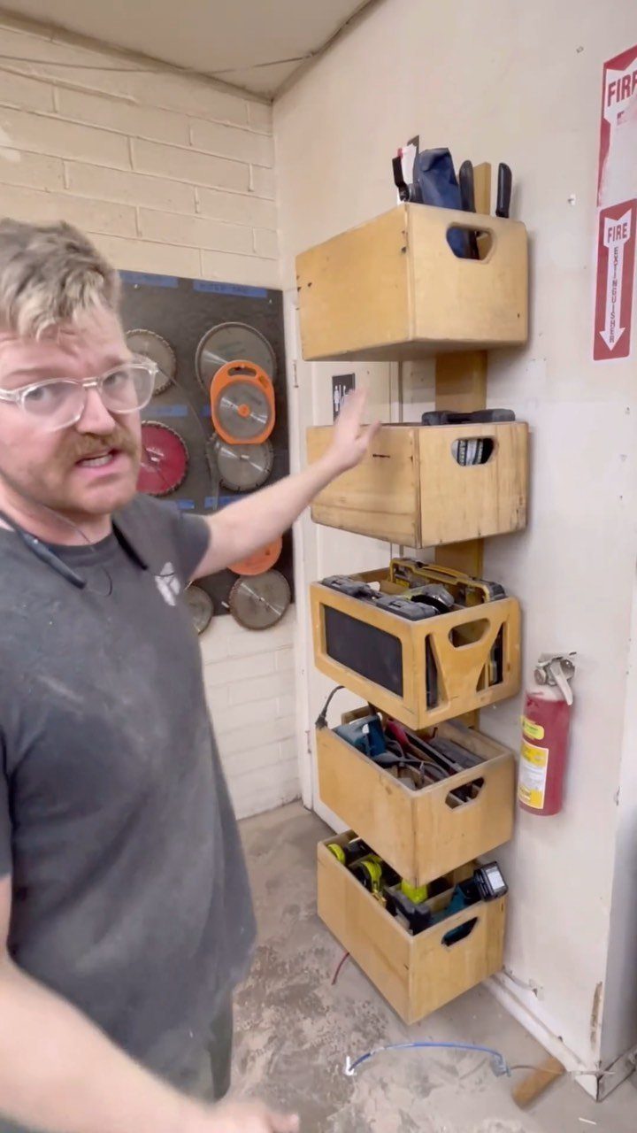 9 Garage Design Interior Ideas for Workspace, Storage and Style 3 A man pointing at a vertical storage system made of wooden crates mounted on a wall.