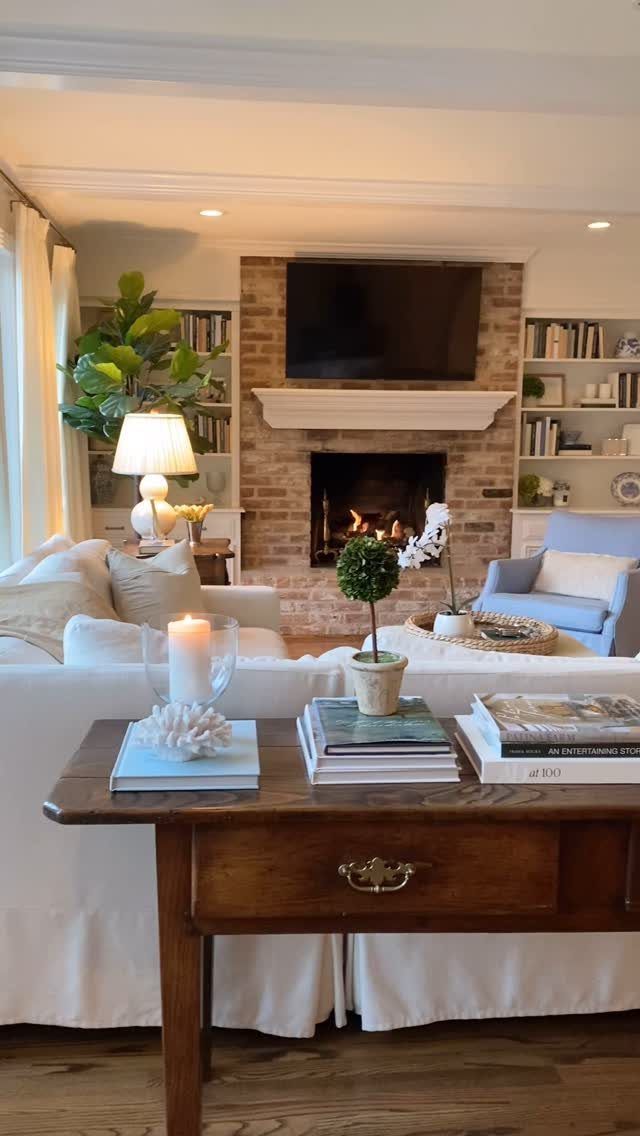Garage to Family Room Conversion: 8 Ideas for 2026 4 A warm living room with a brick fireplace, glowing fire, and comfortable white seating.