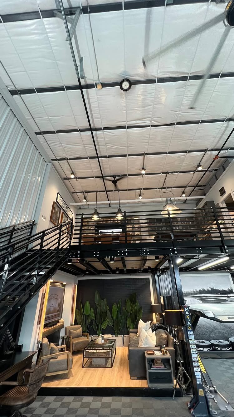 Garage to Family Room Conversion: 8 Ideas for 2026 8 Industrial loft space with a mezzanine, black metal stairs, and comfortable grey lounge seating.
