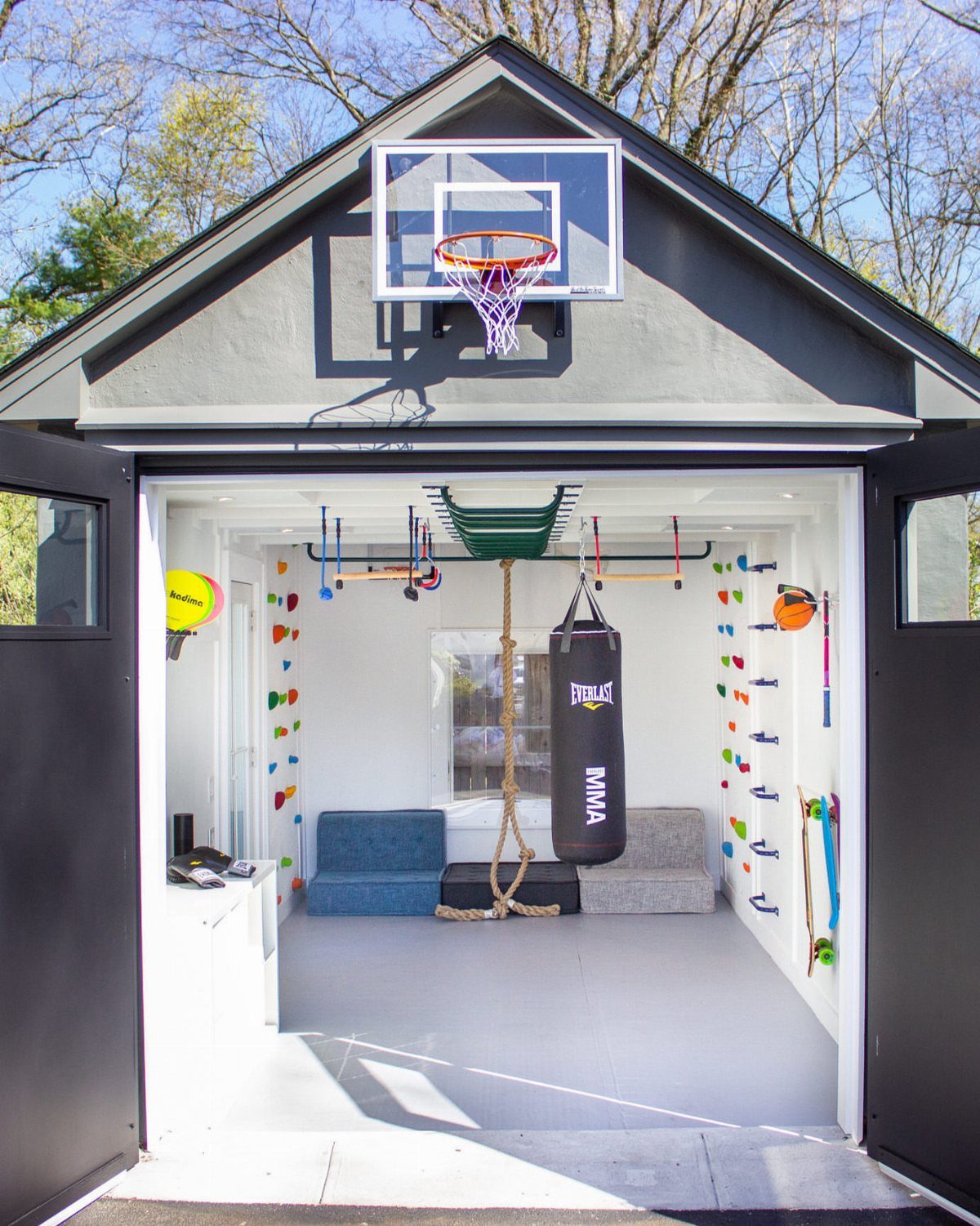 Garage to Family Room Conversion: 8 Ideas for 2026 5 A converted garage space filled with climbing walls, a punching bag, and gymnastic equipment for children.