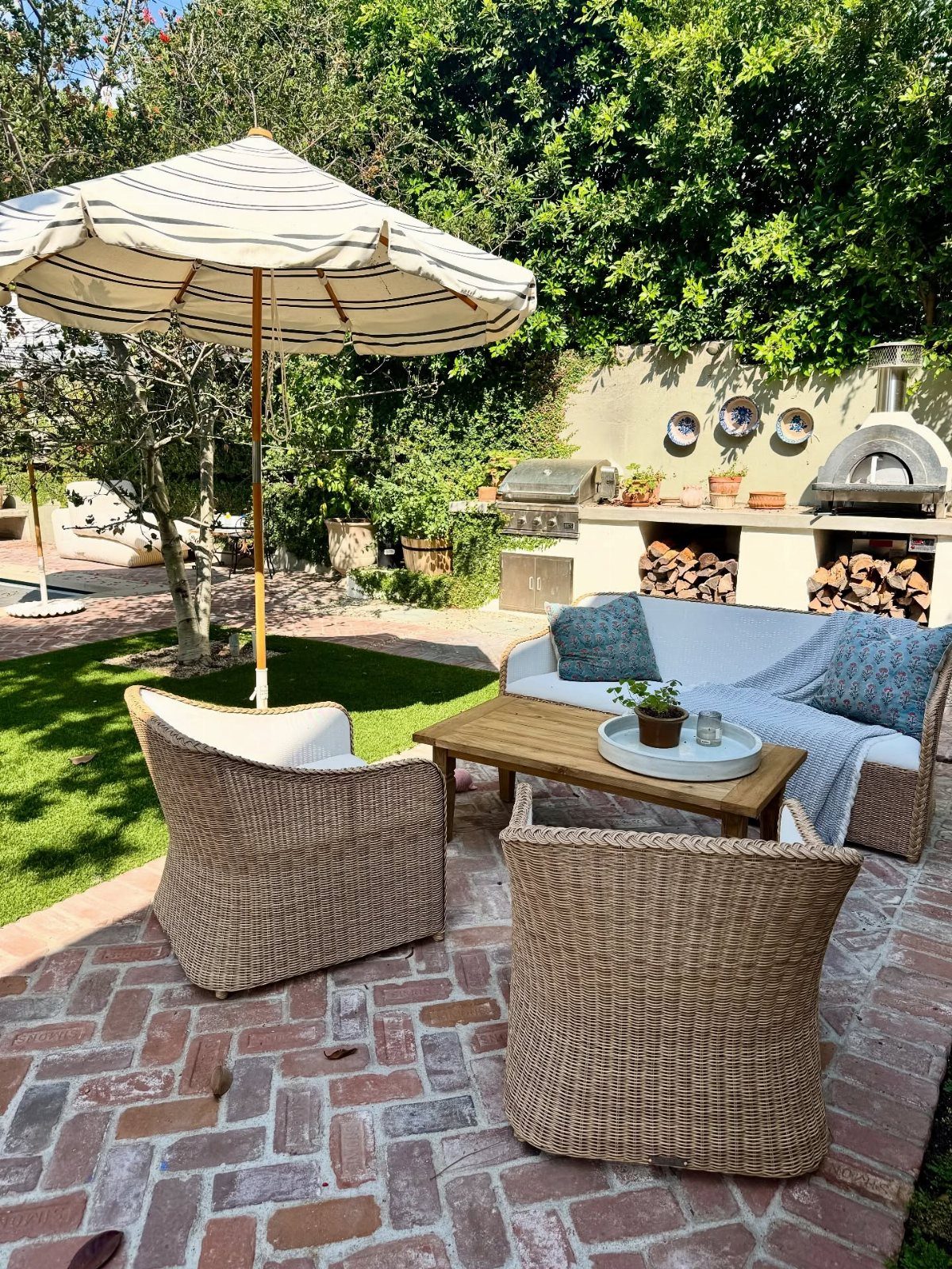 22 Backyard Garden Ideas for Patios, Beds, and Privacy 1 Wicker armchairs and a white sofa arranged around a wooden coffee table on a brick patio.