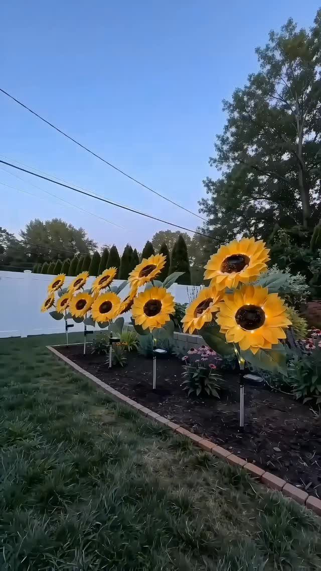 22 Outdoor Backyard Ideas for Dining, Gardens, and Gathering Spaces 4 Large yellow artificial sunflowers on metal stakes planted in a brick-lined garden bed.