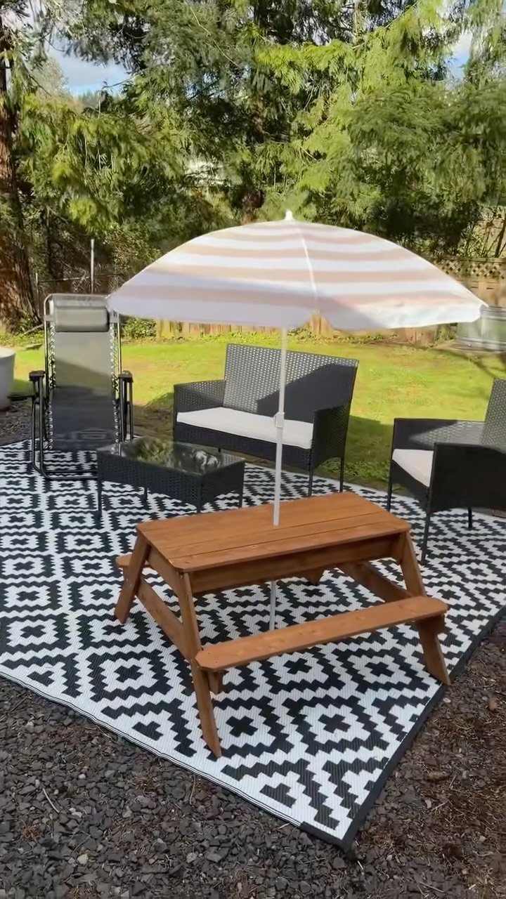22 Outdoor Backyard Ideas for Dining, Gardens, and Gathering Spaces 14 Black and white geometric patterned rug under a wooden picnic table and patio furniture.