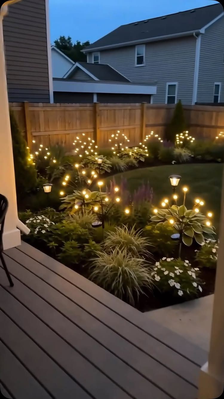 29 Outdoor Gardens Ideas for Patios, Yards, and Every Budget 20 Small glowing garden lights illuminating various green plants and flowers in a backyard at dusk.