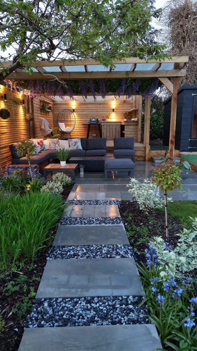 29 Outdoor Gardens Ideas for Patios, Yards, and Every Budget 26 A wooden pergola shading a modern outdoor living room with grey sofas and lush greenery.