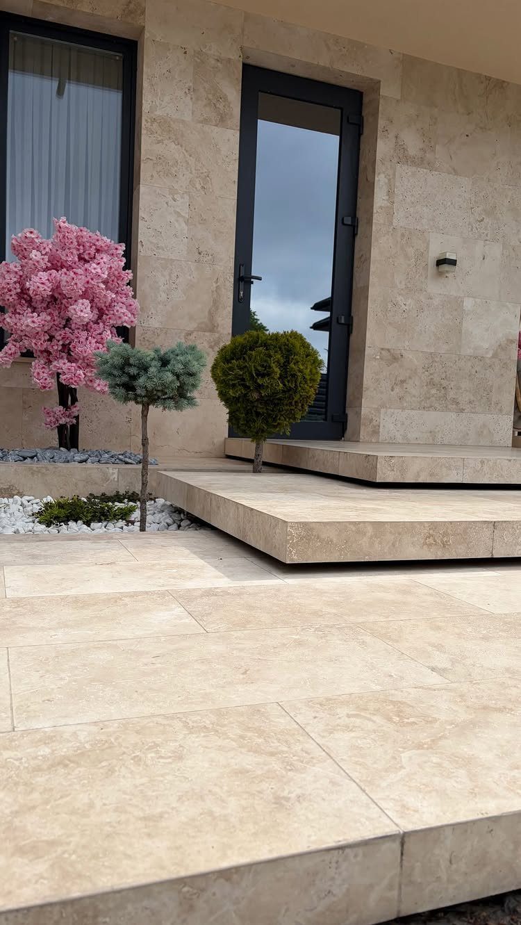 29 Outdoor Gardens Ideas for Patios, Yards, and Every Budget 8 Wide beige stone steps and patio leading to a modern building with small ornamental trees.