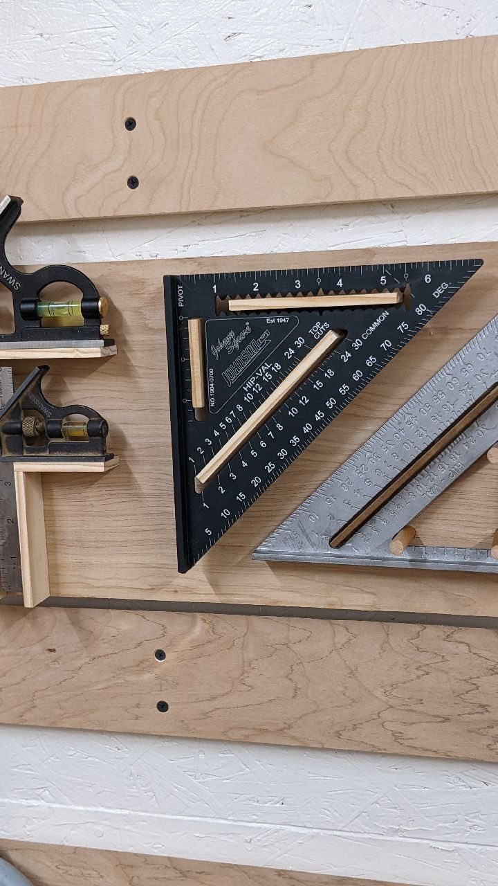 Tool Shed Storage: 12 Ideas for Lawn Gear, Power Tools & Hardware 6 Wooden dowel tool holders securing a speed square and framing square on a plywood wall.
