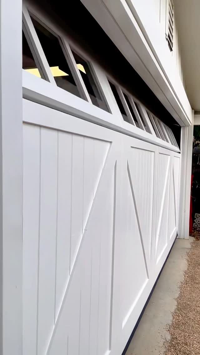 White wooden garage door with geometric paneling and small windows at the top.