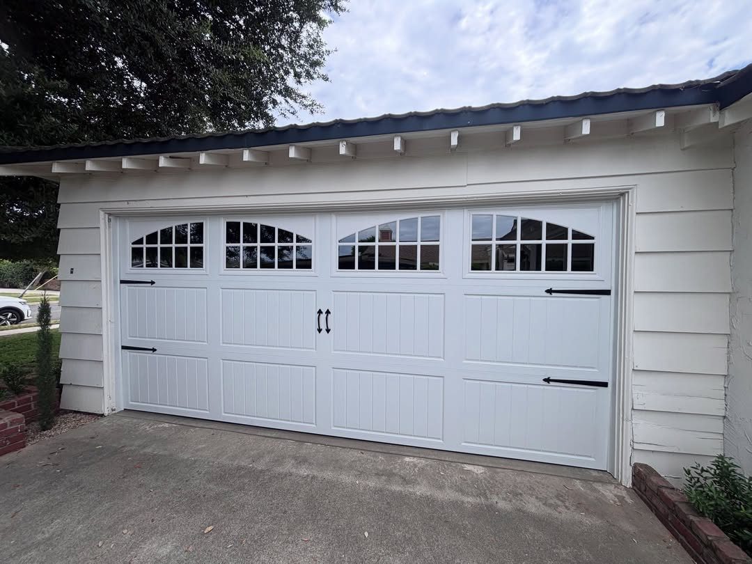 White carriage house garage door with black hardware and window panes on a white building.