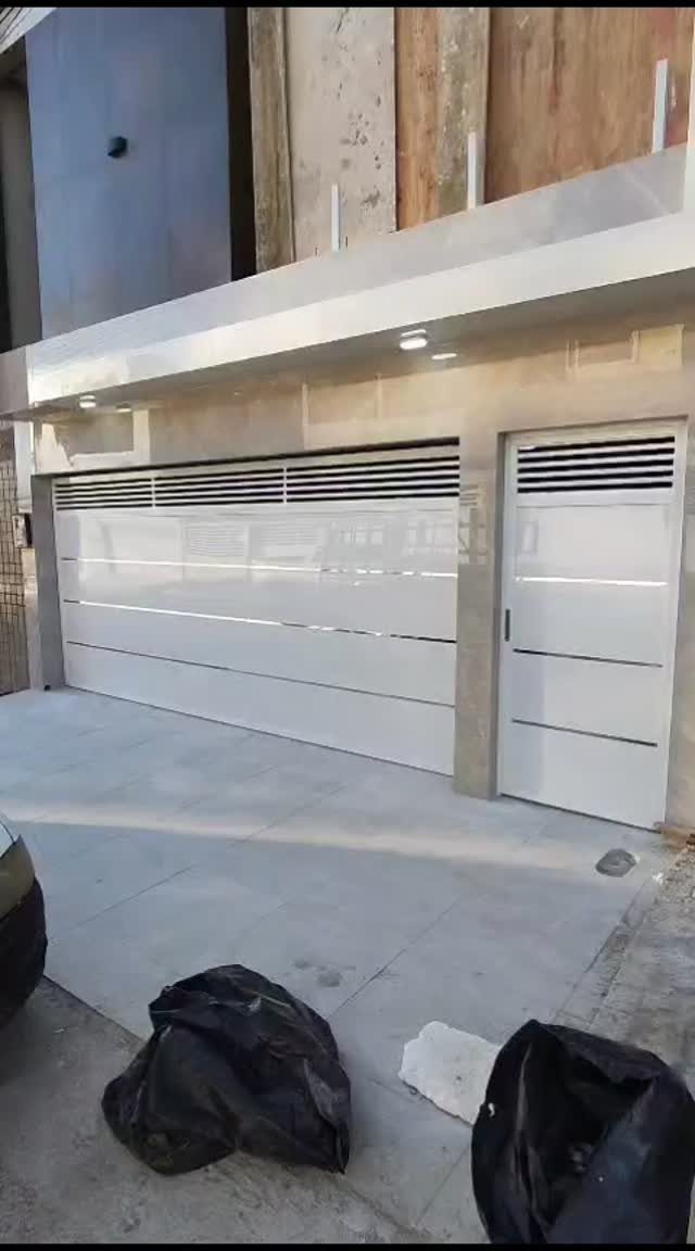 White modern garage doors and a matching pedestrian door on a stone building facade.