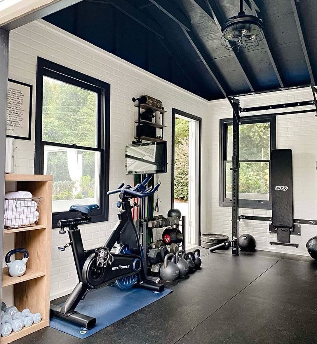 A fully equipped home gym with a stationary bike, kettlebells, and weightlifting equipment.