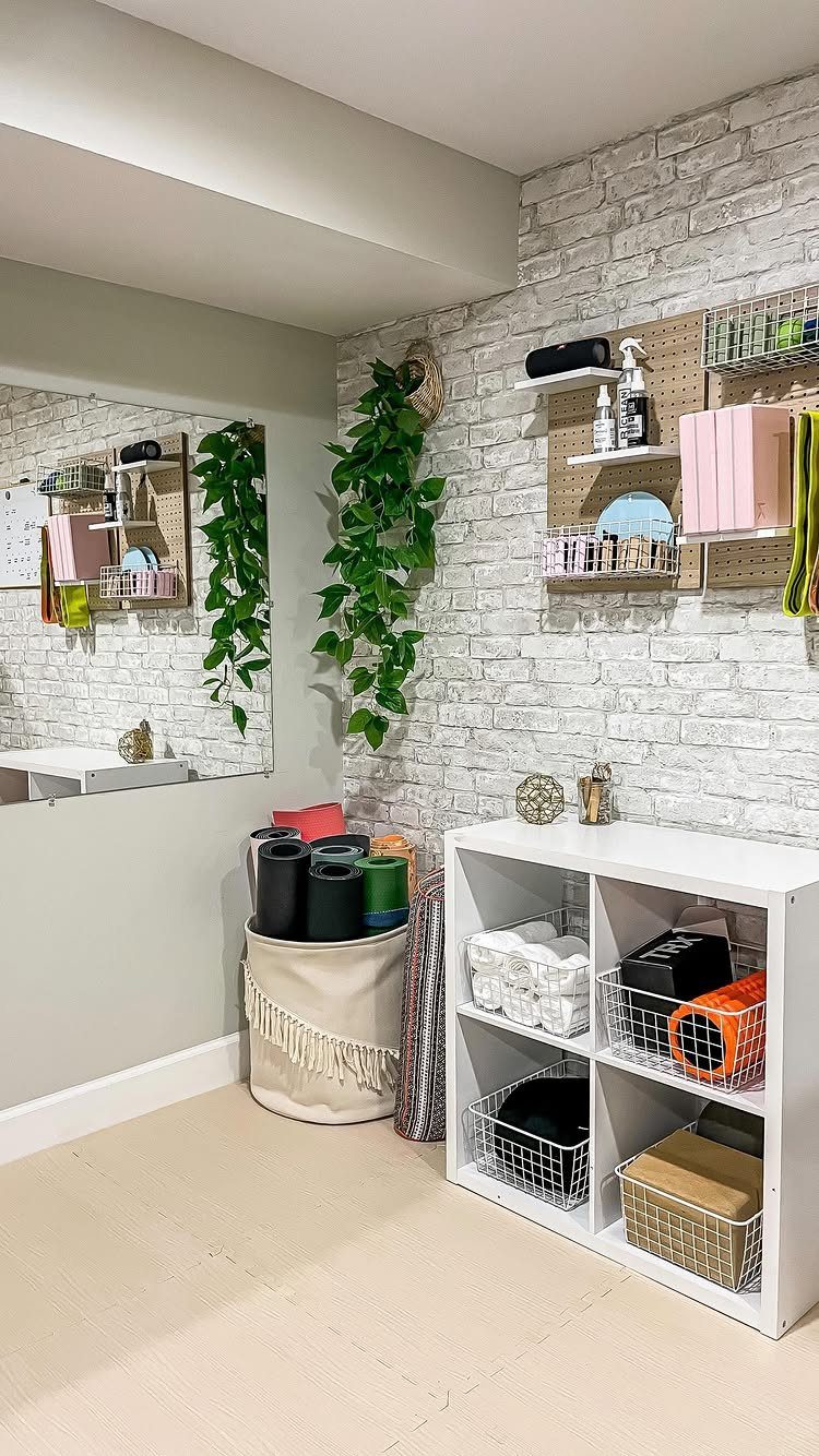 White faux brick wall decorated with wooden shelves and greenery in a home gym.